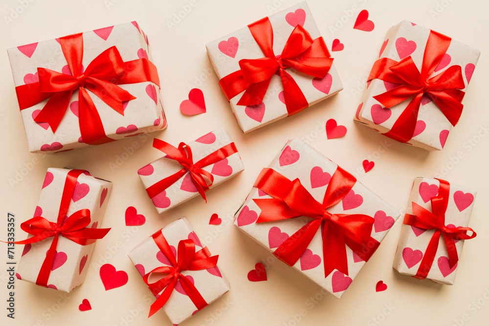 Top view photo of valentine day decorations gift box with red ribbon bow on colored background. Holiday gift boxes with top view