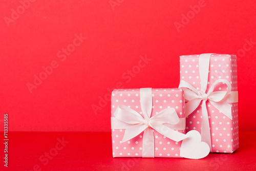 gift box with red bow and red heart on colored background. Perspective view. Flat lay © sosiukin