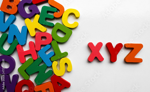English Alphabet On A White Background. alphabets on a wooden surface. xyz - letters. scattered mixed colorful wooden letters of the English alphabet on backdrop, copy space, background composition