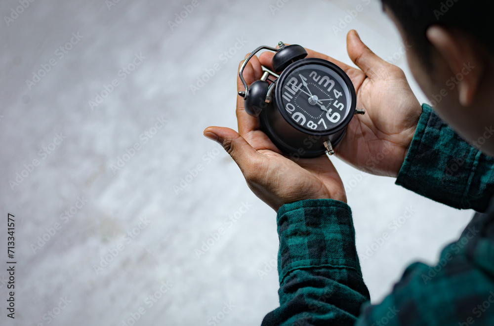 Time management concept. Asian man looking at Black retro alarm clock. Time to wake up for the morning routine Time management concept. Asian man looking at Black retro alarm clock. Time to wake up for the morning routine