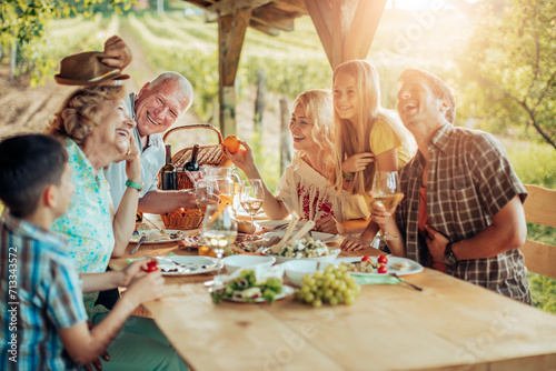 Happy family enjoying meal together in vineyard photo