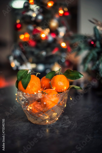 Tangerines in a crystal bowl against the background of New Year's lights. New Year's still life