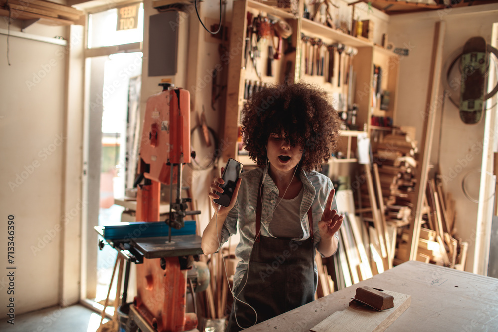 Artisan woman dancing in woodworking workshop