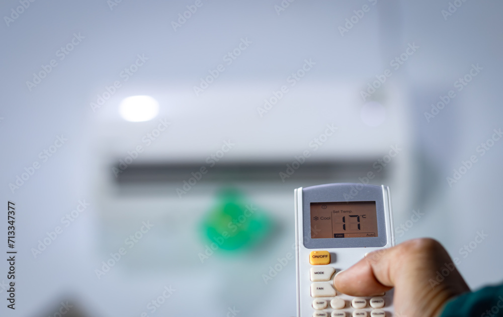 Man's hand holding remote control directed at air conditioner. Man's hand holding remote control directed at air conditioner.