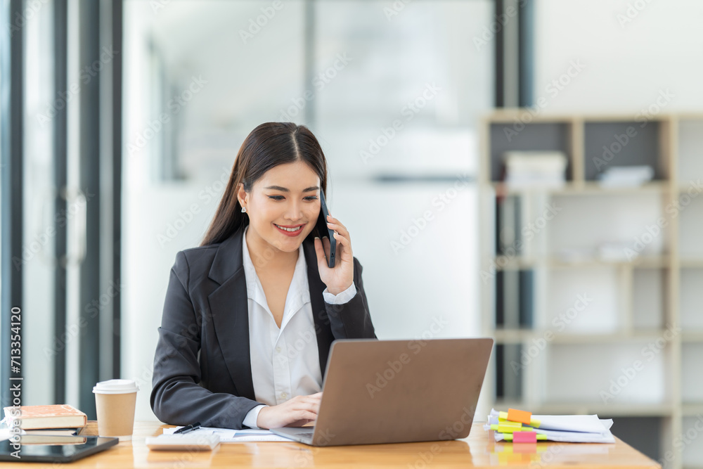 Shot of a young professional woman sitting at desk in front of laptop and using mobile phone working on business contract. Shot of a young professional woman sitting at desk in front of laptop and using mobile phone working on business contract.