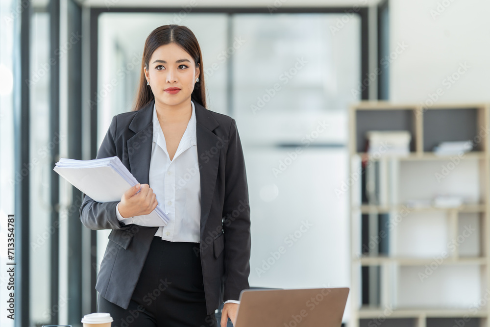 Asian Businesswoman using smartphone for doing finance on an office desk, tax, report, accounting, statistics, and analytical research concept. Asian Businesswoman using smartphone for doing finance on an office desk, tax, report, accounting, statistics, and analytical research concept.