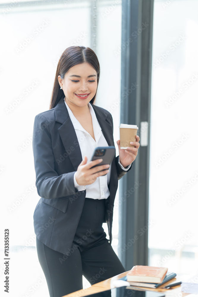 Asian Businesswoman using smartphone for doing finance on an office desk, tax, report, accounting, statistics, and analytical research concept. Asian Businesswoman using smartphone for doing finance on an office desk, tax, report, accounting, statistics, and analytical research concept.