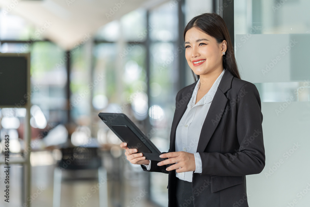 Portrait of beautiful young woman standing in front of glass board and smiling on camera. Female office worker using laptop in company. Portrait of beautiful young woman standing in front of glass board and smiling on camera. Female office worker using laptop in company.