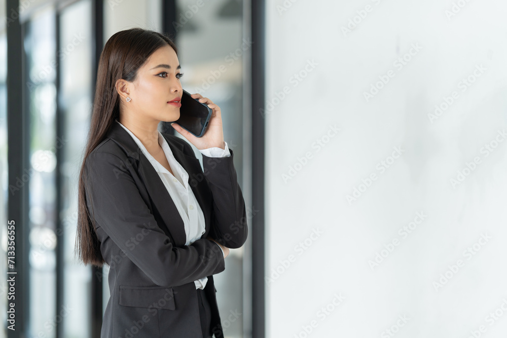 Sharing good business news. Attractive young businesswoman talking on the mobile phone and smiling while sitting at her working place in office and looking at laptop PC. Sharing good business news. Attractive young businesswoman talking on the mobile phone and smiling while sitting at her working place in office and looking at laptop PC.