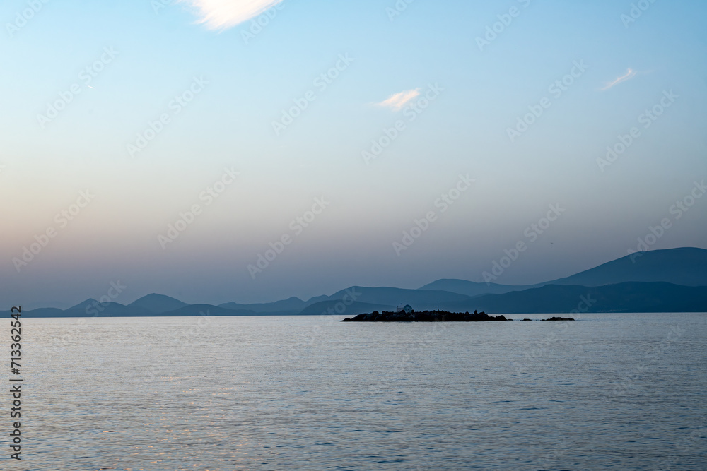 A monastery on a tiny island at sunset viewed from Kamini Harbor on Hydra Island, Greece