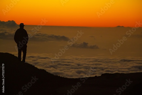 Silhouette of a Man Overlooking Sea of Clouds at Sunset