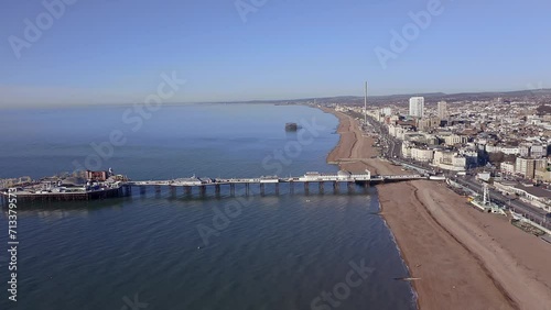 Aerial footage along Brighton Beach towards the Victorian Palace Pier, a popular seaside resort in East Sussex England.