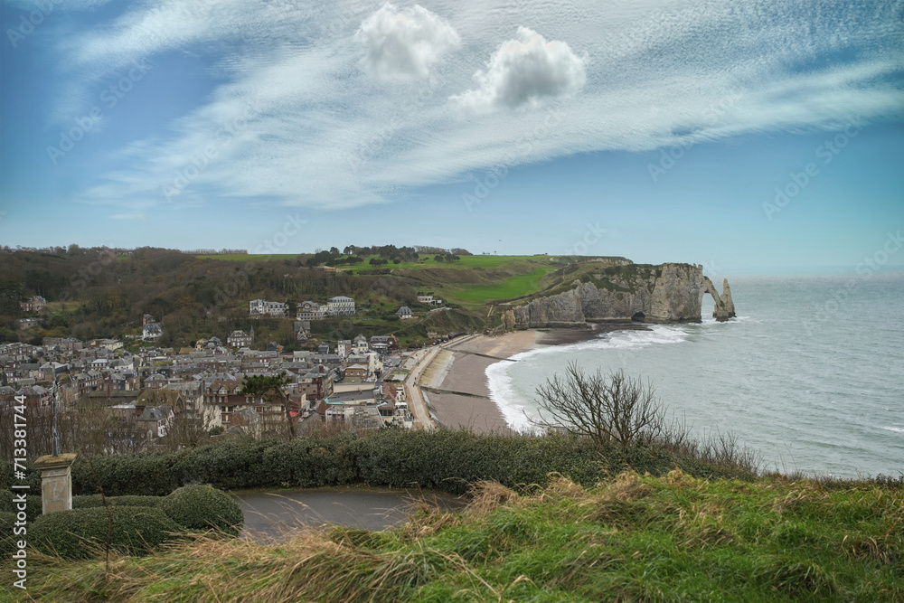 Etretat in Normandy, the famous cliffs and needle on the pebble beach, and the village
