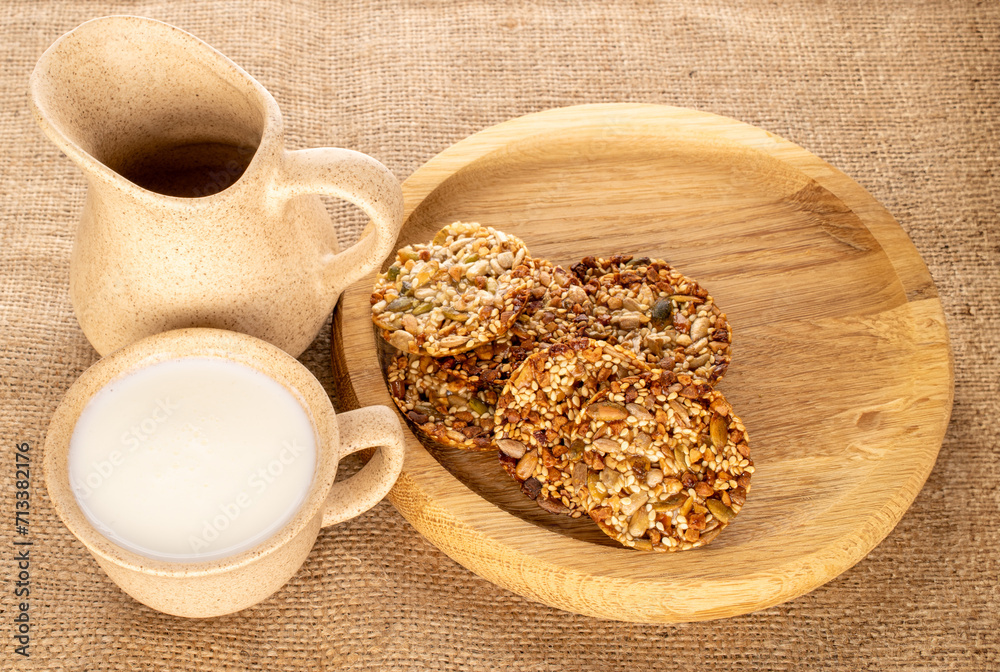 Several Thaler cookies with nuts, honey and sour cream cup with wooden tray on jute cloth, macro. Several Thaler cookies with nuts, honey and sour cream cup with wooden tray on jute cloth, macro.