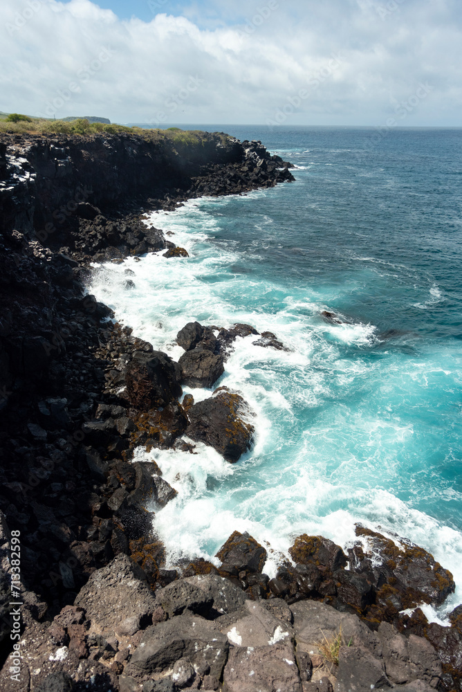 beach landscape with the sea and waves and cliffs of the coasts of the Galapagos Islands in the Pacific Ocean with blue and green water and volcanic rocks