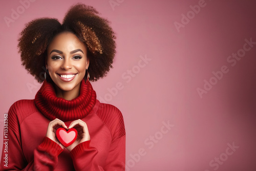 Young african american curly hair woman wearing red sweater smiling and showing red heart and heart shape with hands on soft pink background. Valentine Day Love Beautiful concept. Banner copy space