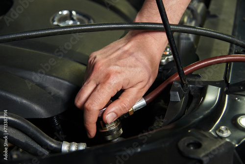 Hands of the master in cars and various car parts. Car engine, bumper, metal parts of the car. The master makes a car repair in a car repair shop.