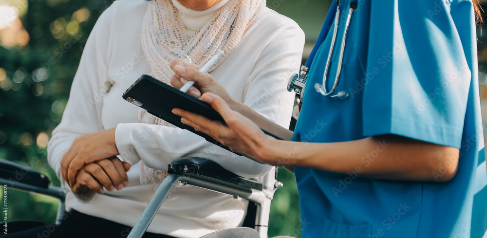 Nursing staff talking to an elderly person sitting in a wheelchair. - obrazy, fototapety, plakaty 