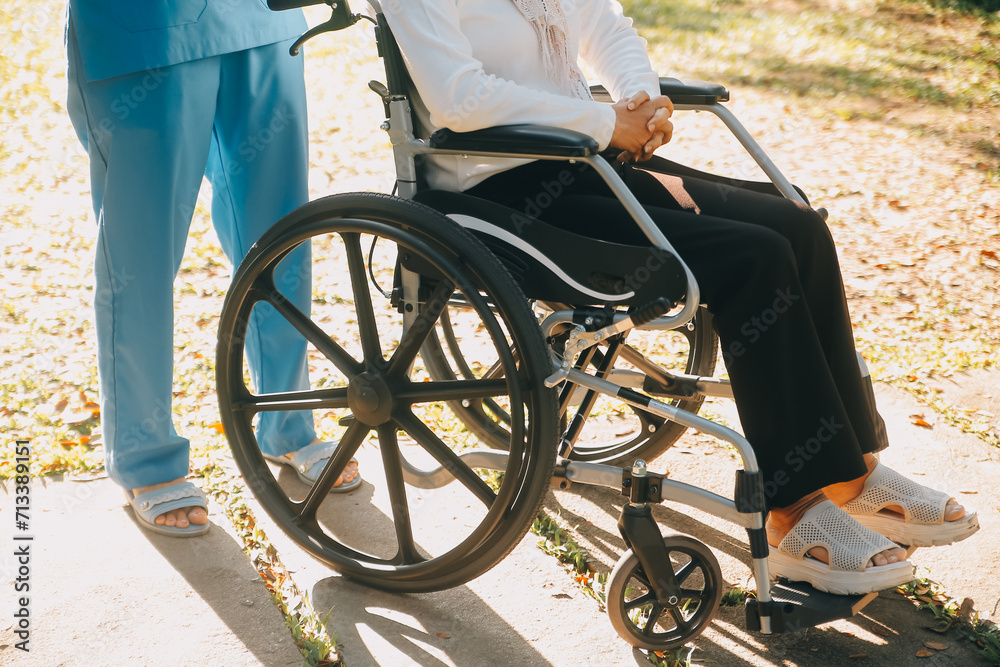 Nursing staff talking to an elderly person sitting in a wheelchair.