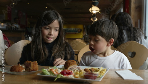 Kids eating food at diner  children enjoying cozy restaurant  siblings little brother and sister