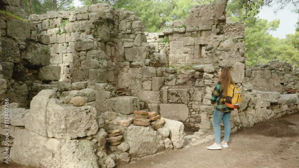 Ruined houses and stone walls of the ancient city of Phaselis in the forest. A female traveler examines them. Ruined houses and stone walls of the ancient city of Phaselis in the forest. A female traveler examines them.