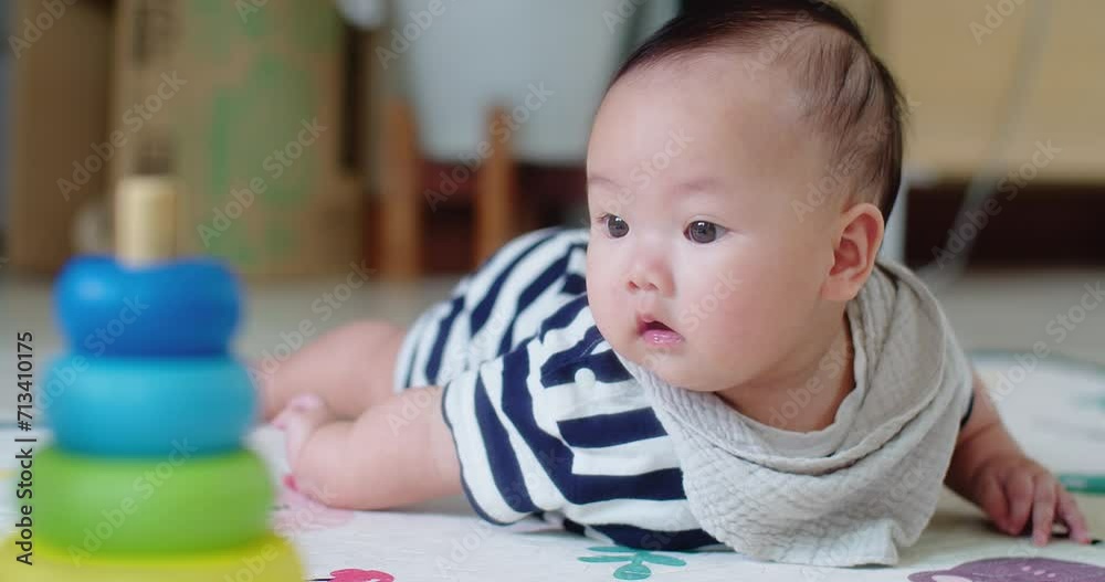 adorable baby lies on floor, gazing curiously at vibrant stacking rings, capturing a moment of early childhood development, Infant focused on colorful stacking rings while practicing crawling adorable baby lies on floor, gazing curiously at vibrant stacking rings, capturing a moment of early childhood development, Infant focused on colorful stacking rings while practicing crawling