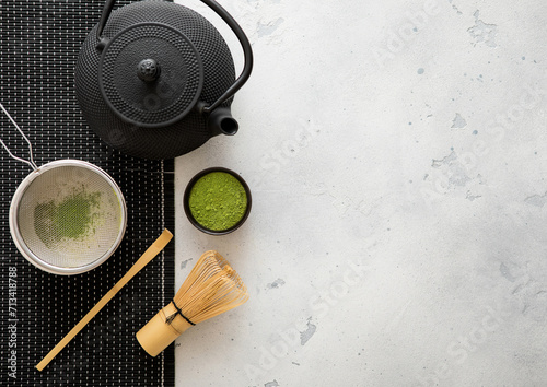 Japanese iron kettle with matcha green tea powder with whisk and spoon and bowl with sifter on white background.Top view.
