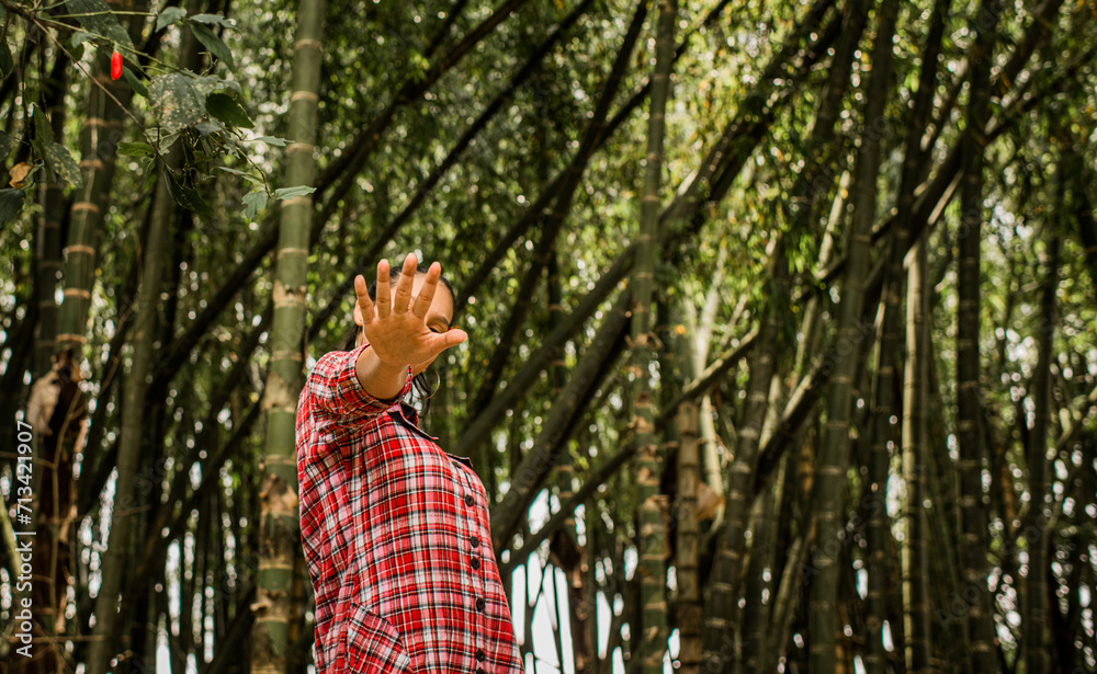 mujer joven al aire libre con muchos árboles mientras se cubre la cara con las manos