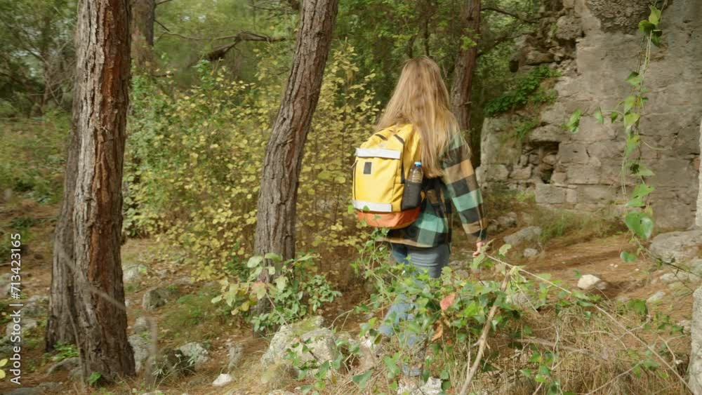 A young woman tourist explores the walls of ancient ruined houses overgrown with pine forest for thousands of years. A young woman tourist explores the walls of ancient ruined houses overgrown with pine forest for thousands of years.