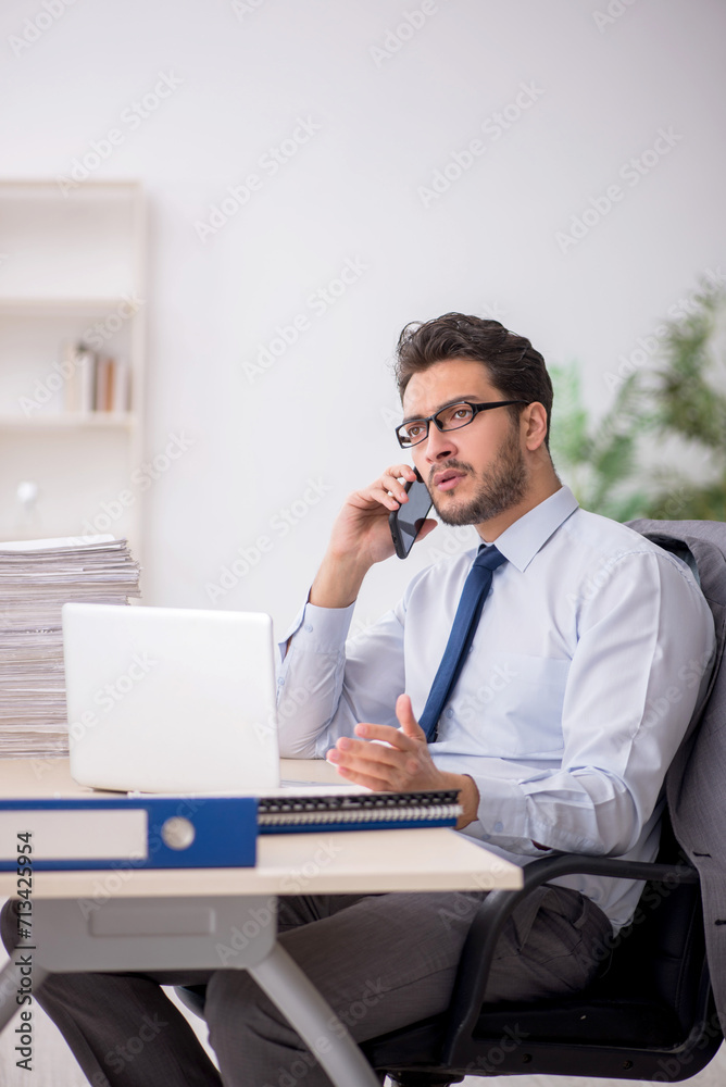 Young male employee and too much work in the office Young male employee and too much work in the office