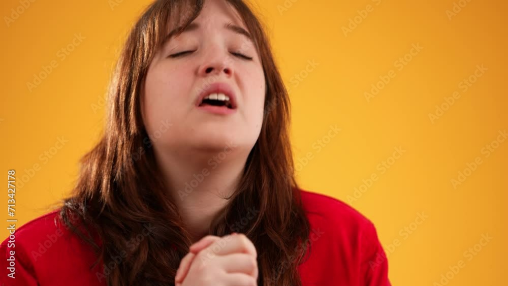 Holding hands folded in prayer begging making wish keep fingers crossed portrait of pretty brunette young woman 20s isolated on yellow background studio with copy space in slow motion Holding hands folded in prayer begging making wish keep fingers crossed portrait of pretty brunette young woman 20s isolated on yellow background studio with copy space in slow motion