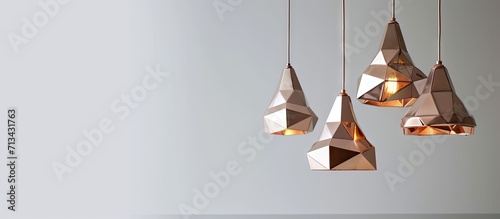 Creative modern chandelier with geometric shaped lampshade and copper details hanging against white wall. Copy space image. Place for adding text photo