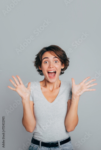 Close up vertical photo of young woman wearing casual clothes and celebrating excited and amazed for success with palms raised and open eyes screaming shocked. Bet win or lottery
