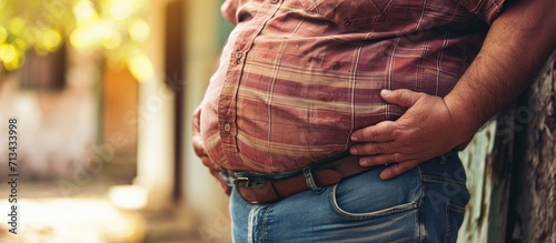 A stock photo of a fat man sitting on a sofa focused on his belly. Copy space image. Place for adding text