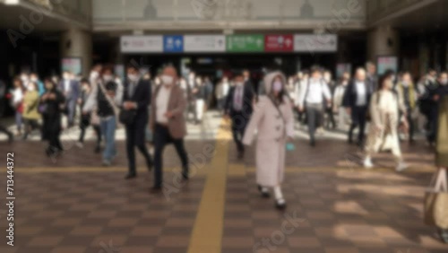 Slowmotion and blurred defocused view of a commuters exiting the metro station in Japan, rushing to get to their workplaces. A bustling crowd of people march down the busy street photo