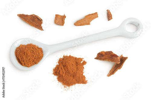 Cinnamon powder in ceramic spoon with cinnamon stick crushed isolated on white background. Top view. Flat lay.