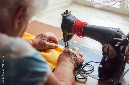 senior woman sewing her cloth with old sewing machine