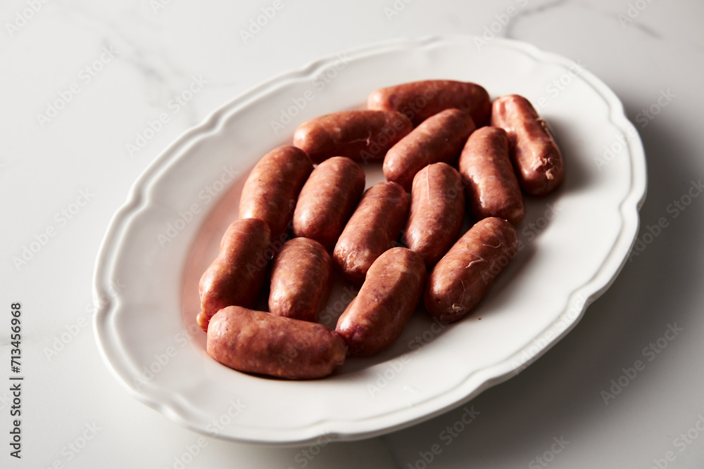 Mini pork sausages on white marble background. Raw and uncooked. Mini pork sausages on white marble background. Raw and uncooked.