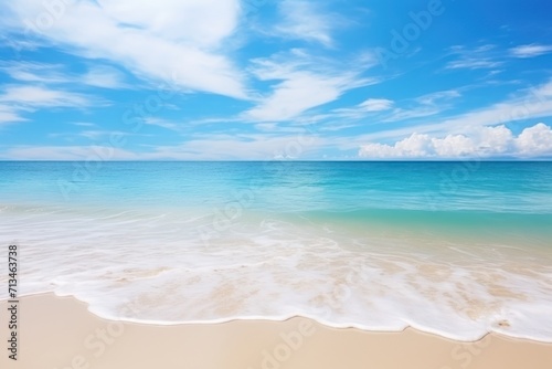  a sandy beach with waves coming in to the shore and a bright blue sky with white clouds in the background.
