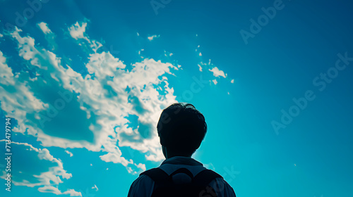 A boy photographed from behind looking at the sky. Space for text.