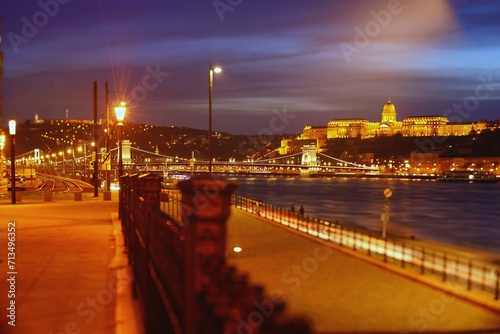 Budapest, Hungary - December 4, 2023: Royal Palace or the Buda Castle and the famous chain bridge after sunset with lights illuminated in danube river in Budapest Hungary. Focus tilted to the bridge. #713496352