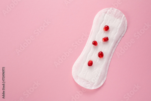 Feminine hygiene pad with red pomegranatered menstrual pad on red background. First menstrual period concept. Copy space photo