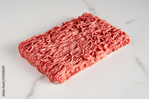 Raw and Fresh Minced Beef on white marble background. Minimalistic food photo, high-key. 