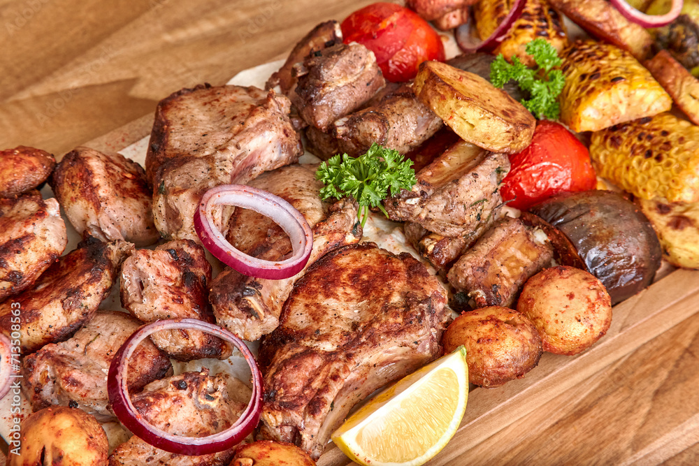 Part of the wooden board with fried meat and vegetables on the wooden table, shallow depth of field. Beef meat and onion in focus