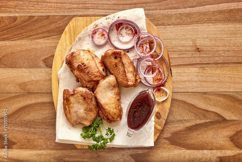 Fried chicken meat with red onion rings, sauce and pita bread on the wooden board on the wooden table, flat lay top view