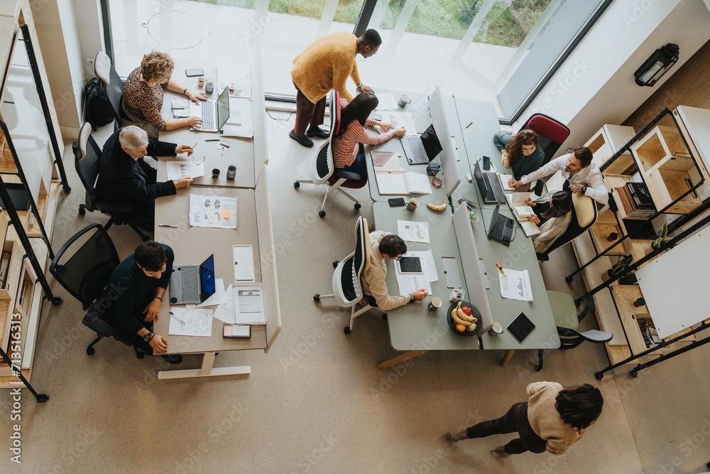 Top angle view photo of employees collaborating indoors, discussing and sharing ideas. Productive and creative teamwork in a successful workplace.