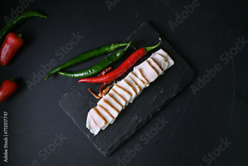 pieces of lard, top view of bacon with red pepper on a black background, 