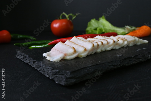 pieces of lard, top view of bacon with red pepper on a black background, 