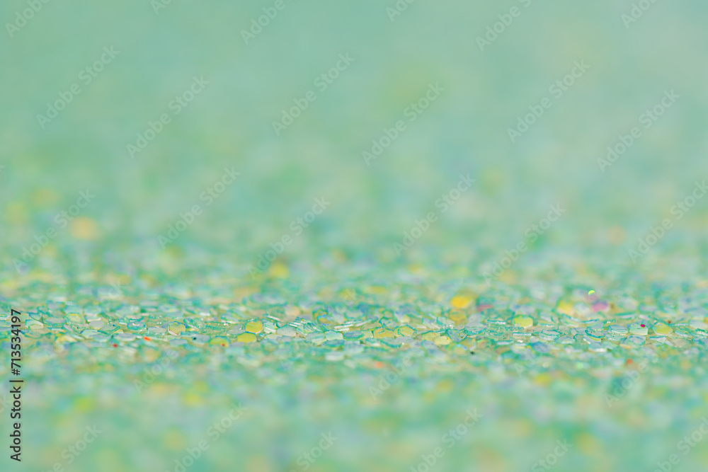 Green background with a thin focal part and a main part in defocus. Macro photo of glitter paper. Green background with a thin focal part and a main part in defocus. Macro photo of glitter paper.