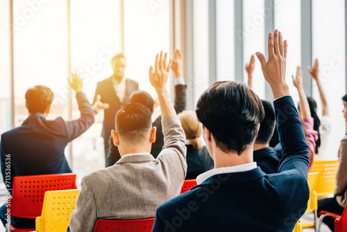Businesspeople in a boardroom participate in a strategy session with a meeting and seminar. Questions spark active engagement with hands raised by colleagues and employees. photo